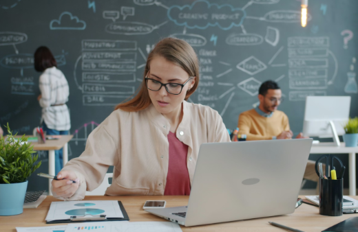 Woman Sitting at a Desk and Working on a Laptop